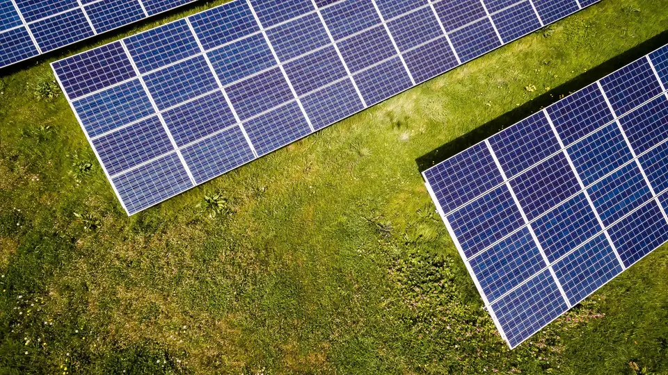 Vista aérea de filas de módulos fotovoltaicos sobre un prado